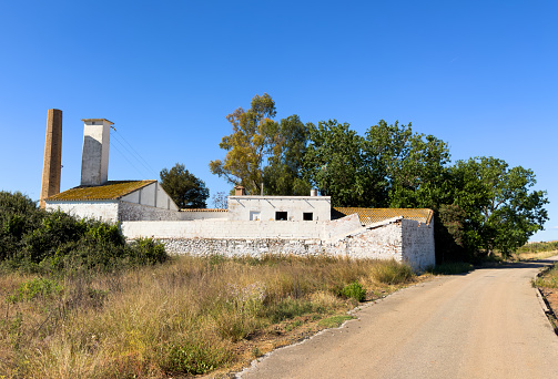 Farm building near farm field. Rural landscape. Farm house on farmland. Old Home in Spain countryside. Farmhouse and Valencian vegetable garden on farmland. Cultivation of crops and orange harvesting.