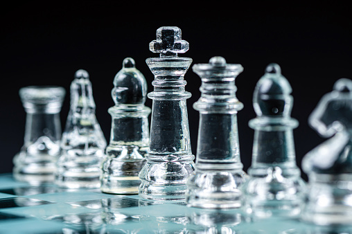Transparent glass chess pieces on dark background. Leadership ,confrontation and  strategy concept