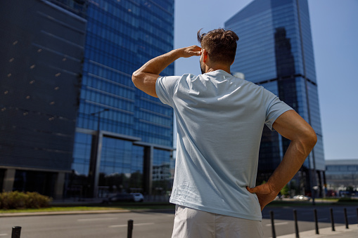 Back view of an unrecognizable person in casual clothes standing against backdrop of skyscrapers