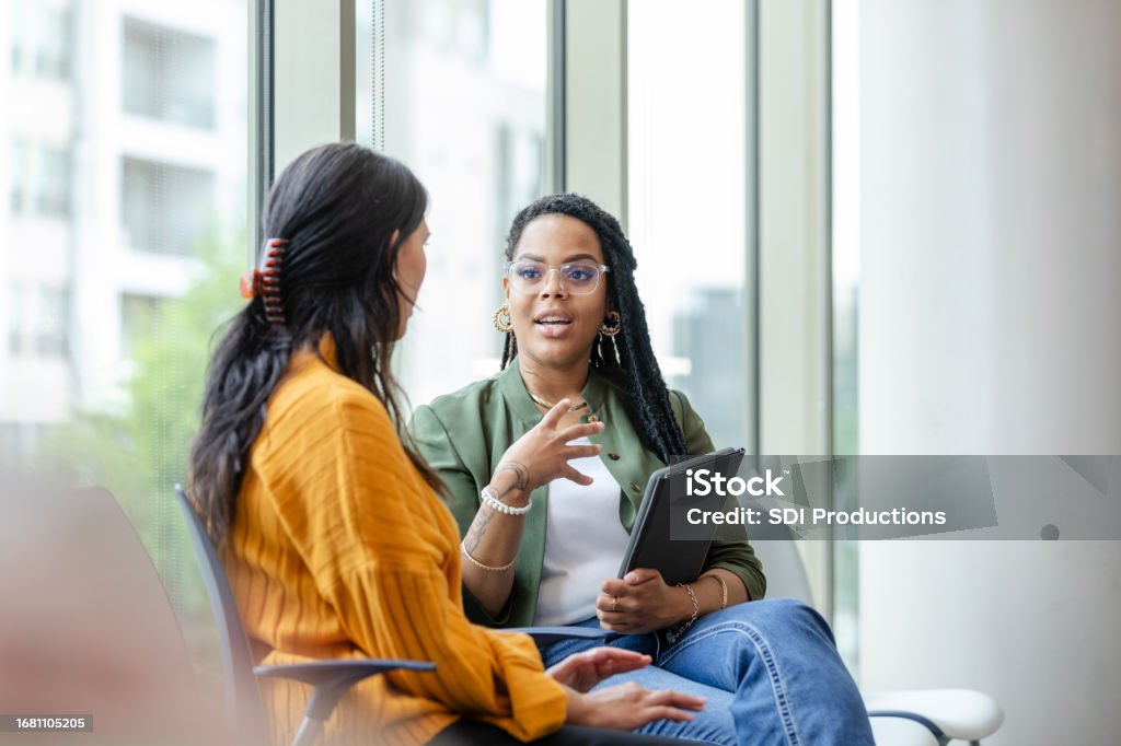Therapy client listens to therapist discuss coping strategy A female therapy patient listens attentively to a female therapist discuss coping strategies. Discussion Stock Photo