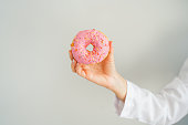 female healthy nutritionist holding donut with her hand