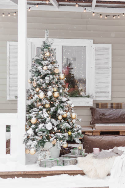 The porch of a country house decorated for Christmas and New Year holidays. Christmas tree on the porch of the house in winter. stock photo