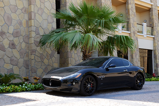 Dubai, UAE - September 9, 2013: The luxury Maserati Granturismo car is near luxurious hotel. Hotels in Dubai attracted over 11 million guests in 2013.