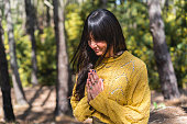 Woman meditates with hands clasped on the woods.