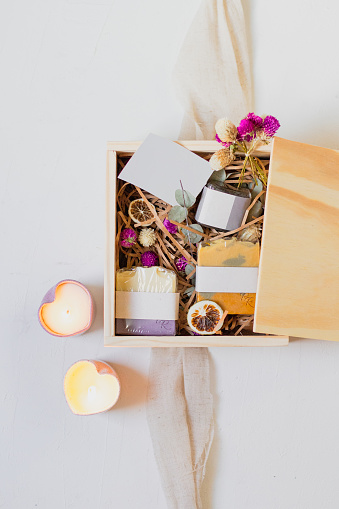 Romantic gift composition. Soap, candles and dried flowers on wooden box.