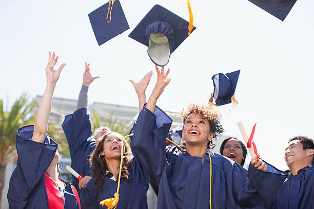 absolventen herumwerfen kappen in der luft - graduation color image people photography stock-fotos und bilder