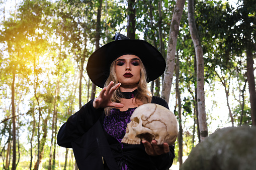 Witch pray the magic with skull in forest , Halloween concept