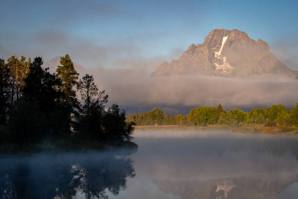 Mt Moran in Foggy Morning Reflection with Trees stock photo