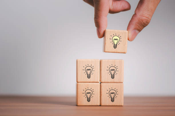 istock ideas and creativity Male hand holding a wooden cube with a light bulb icon on a light background. Working as a team to brainstorm, evaluate, and select for business development. Copy space banner 1681282405