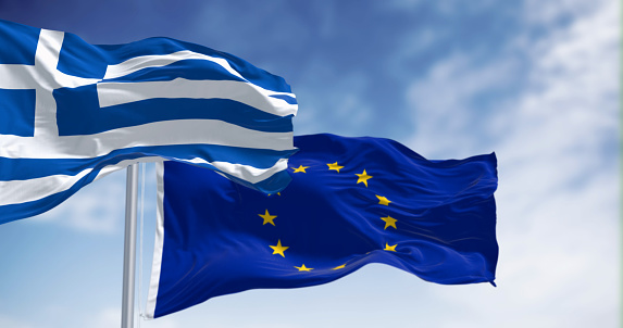 The flags of Greece and the European Union waving together on a clear day. Greece became a member of the European Union on 1981. 3d illustration render. International treaty and diplomacy