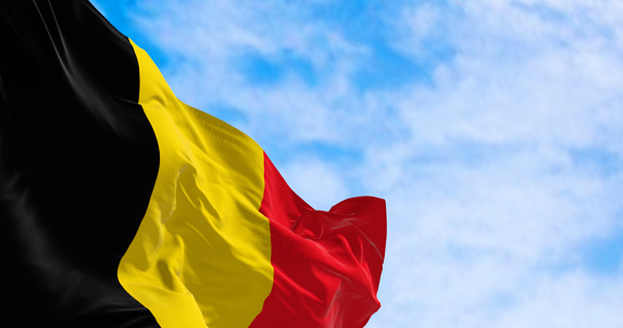 Close-up of the national flag of Belgium waving on a clear day. Three equal vertical bands: black, yellow and red. 3d illustration render. European country. Rippled fabric.