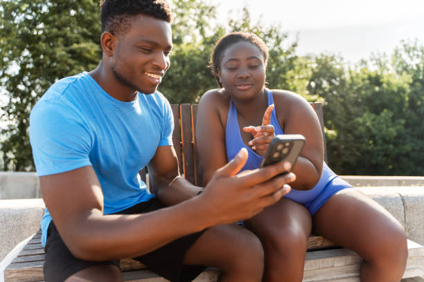 African man holding mobile phone together with african american woman watching video