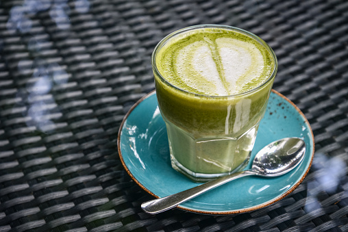 Matcha latte in glass on table in cafe closeup