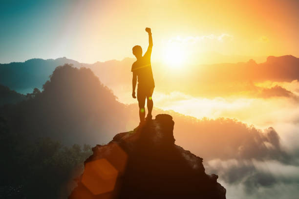 산 정상에서 팔을 들고 축하하는 긍정적인 남자의 실루엣, 언덕 위에 서 있는 남자의 실��루엣, 사업, 성공, 승리, 리더십, 성취 개념. 자유 여행 모험. - climbing achievement leadership adventure 뉴스 사진 이미지