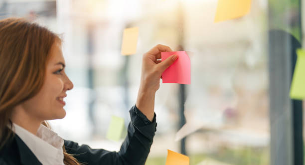 istock Young creative business woman asian using sticker note in glass wall to writing strategy business plan to development growth to success 1681631111