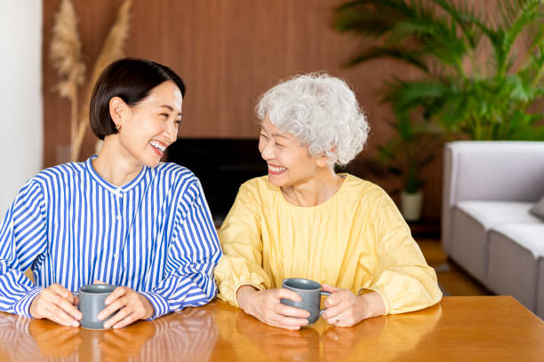 Two Asian women are sitting on chairs and talking.