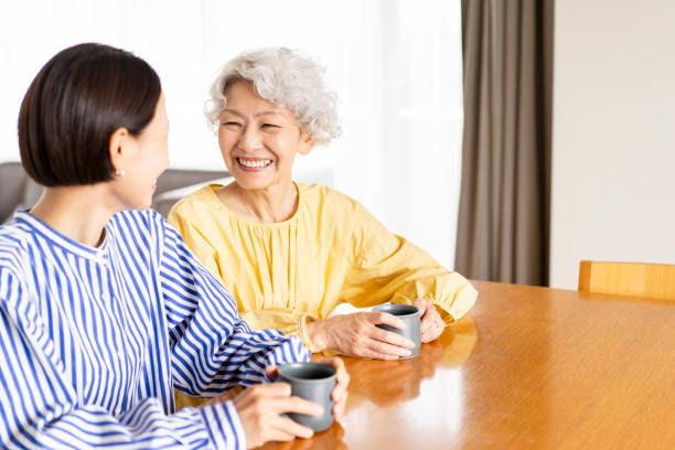 istock Two Asian women are sitting on chairs and talking. 1681637018