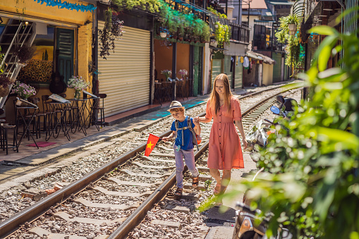 Mother and son travelers walk around railway paths which go through residential area in Hanoi city. Hanoi Train Street is a famous tourist destination. Vietnam reopens after coronavirus quarantine COVID 19.