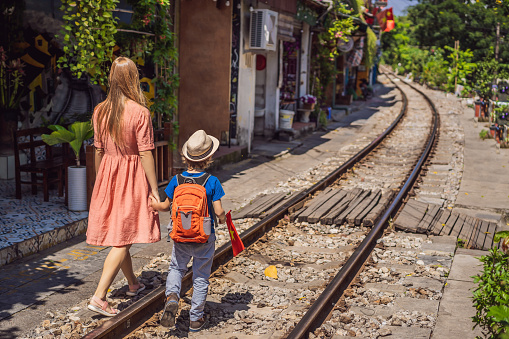 Mother and son travelers walk around railway paths which go through residential area in Hanoi city. Hanoi Train Street is a famous tourist destination. Vietnam reopens after coronavirus quarantine COVID 19.