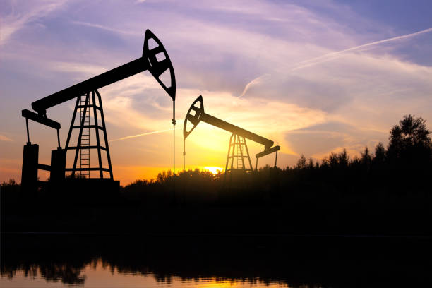 silhouette of oil rigs against the sunset - derrick crane drilling rig well sky imagens e fotografias de stock