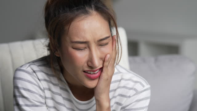 Young Asian woman suffering from toothache.