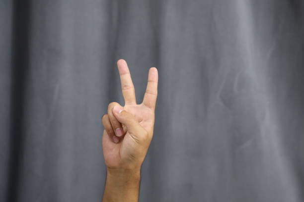 istock Hand show victory or peace sign with gray curtain background, selective focus 1681769539