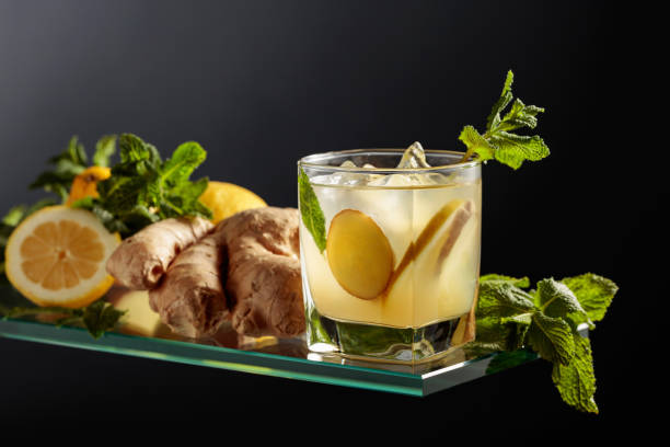 cocktail di birra ginger ale con limone e menta in un bicchiere ghiacciato su sfondo nero. - ginger tea root hot drink foto e immagini stock