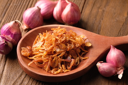 fried shallots in wooden spoon. Indonesian food. food sprinkles. bawang merah goreng.