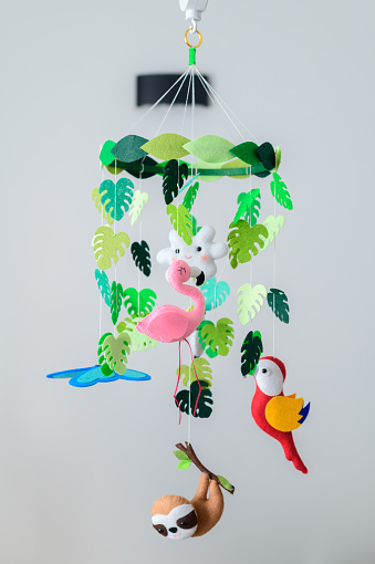 Baby crib mobile hanging in the nursery room, colorful forest-themed cot mobile.