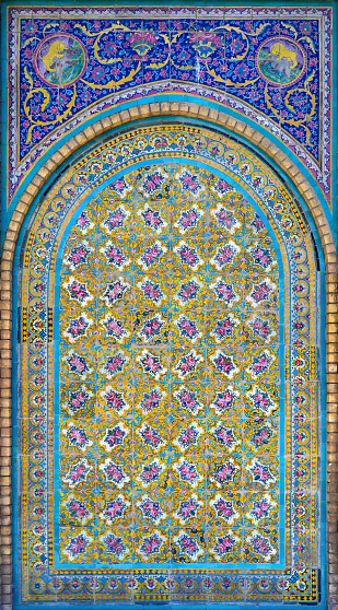 Old, traditional ceramic tiles, pattern of flowers and ornaments, vaulting on the wall in the Golestan Palace complex in Tehran, Iran.