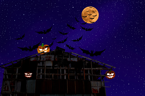 Strawberry supermoon rising over the Halloween pumpkin of an old warehouse roof with flying bats in midnight.
