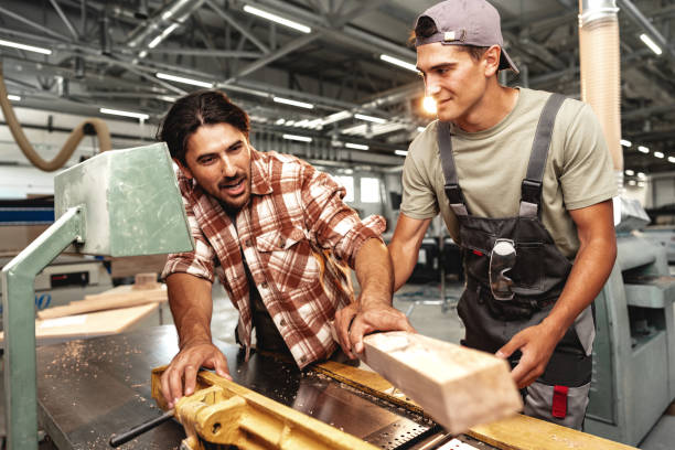 istock Two young carpenters working with wood standing at table in workshop 1681896944