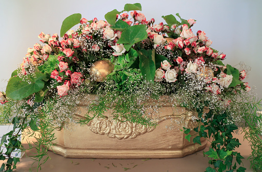 Beautiful flower arrangement with many pink and white roses in a golden painted flower pot