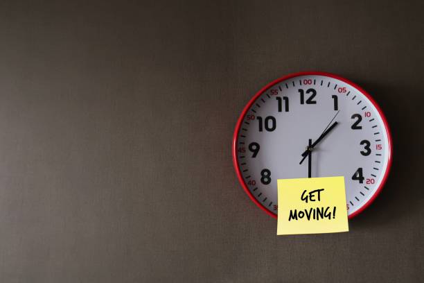 istock Wall clock on gray office wallpaper with handwritten note GET MOVING!, concept of having difficulty setting aside exercise time, reminder for health improvement by being more physically active 1681935832