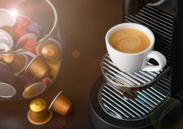White cup with hot aroma coffee from espresso machine pods on dark board.