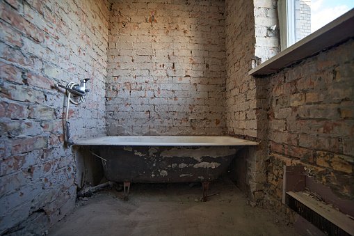Old ussr cast iron bathtube inside abandoned apartment.  Demolition jobs inside house bathroom.