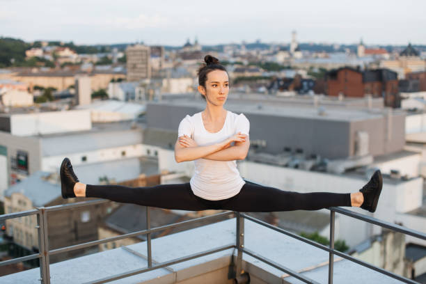 istock Sportswoman doing side split on roof handrails at sunset 1681961245