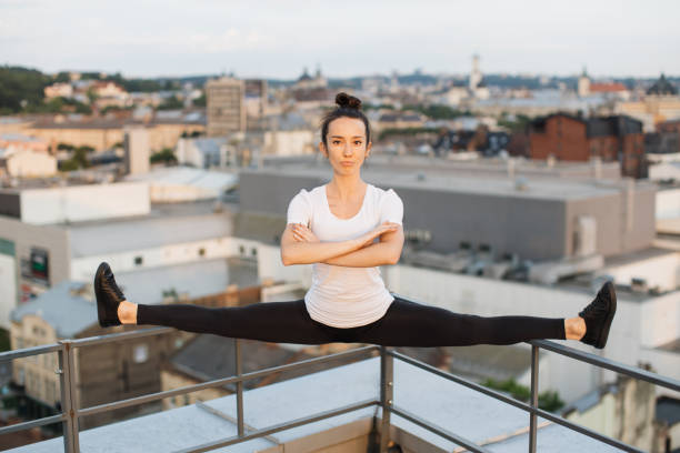 istock Sportswoman doing side split on roof handrails at sunset 1681961263