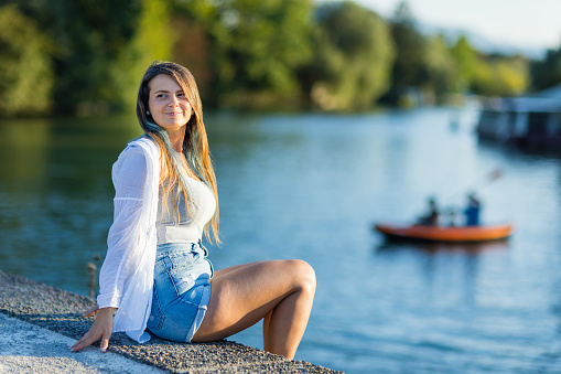 Woman relaxing sitting at river bank of Ljubljanica River.