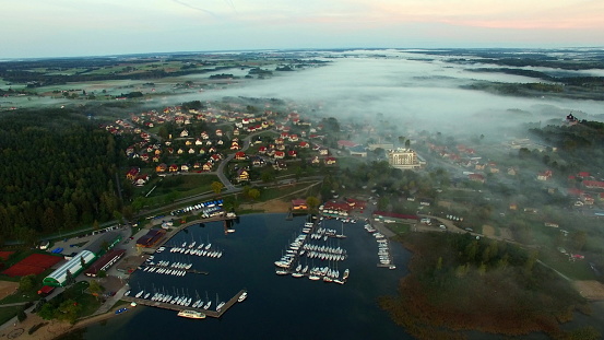 Aerial foggy morning lakeside village and yachts