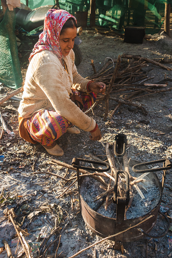 November 30th 2022. Tehri Garhwal, Uttarakhand India. Garhwali woman kindling fire in outdoor cast iron stove, rural Uttarakhand village, winter scene, India
