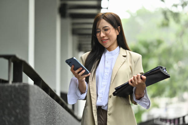 Attractive businesswoman using mobile phone while walking in business district. Technology, communication and people Attractive businesswoman using mobile phone while walking in business district. Technology, communication and people. 6. Social Media Manager stock pictures, royalty-free photos & images