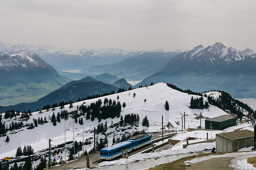 Rigi, Switzerland - April 12, 2022: Blue electric cable tram of Rigi kulm line with alps mountain in background.