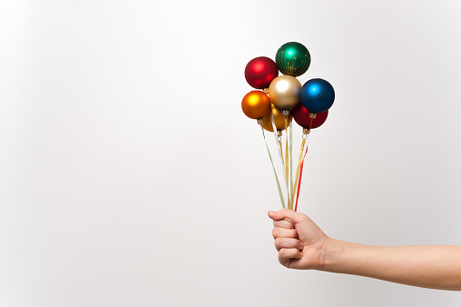 Human hand holding several ropes with levitating New Year balloons bouquet. Conceptual composition