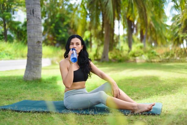 ukrainische schöne frau, die wasser trinkt, nachdem sie draußen yoga auf der karte gemacht hat - exercising sensuality water bottle relaxation exercise stock-fotos und bilder