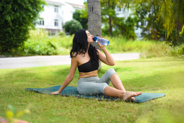 ukrainische schöne frau, die wasser trinkt, nachdem sie draußen yoga auf der karte gemacht hat - exercising sensuality water bottle relaxation exercise stock-fotos und bilder