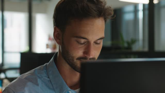 Young caucasian man wearing shirt using computer at desk in office