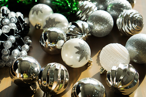 Closeup Christmas tree branch decorated with silver balls and white decor on the table.