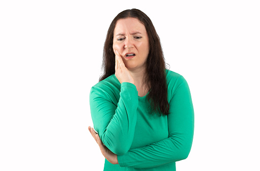 Hispanic woman wearing green casual clothes touching mouth with hand with painful expression due to toothache or dental disease on teeth on white background. dentist