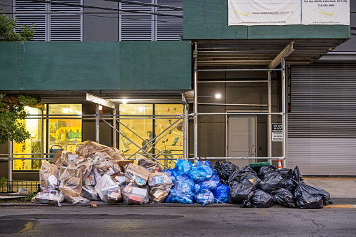 23th street, Long Island City, Queens, New York, USA - August 14th 2023:  Sorted out garbage in different colored bags waiting for pickup under a scaffolding